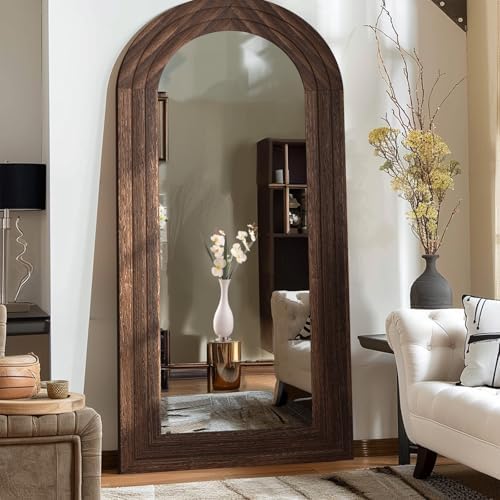 Full length mirror with arched wood frame in a rustic interior setting